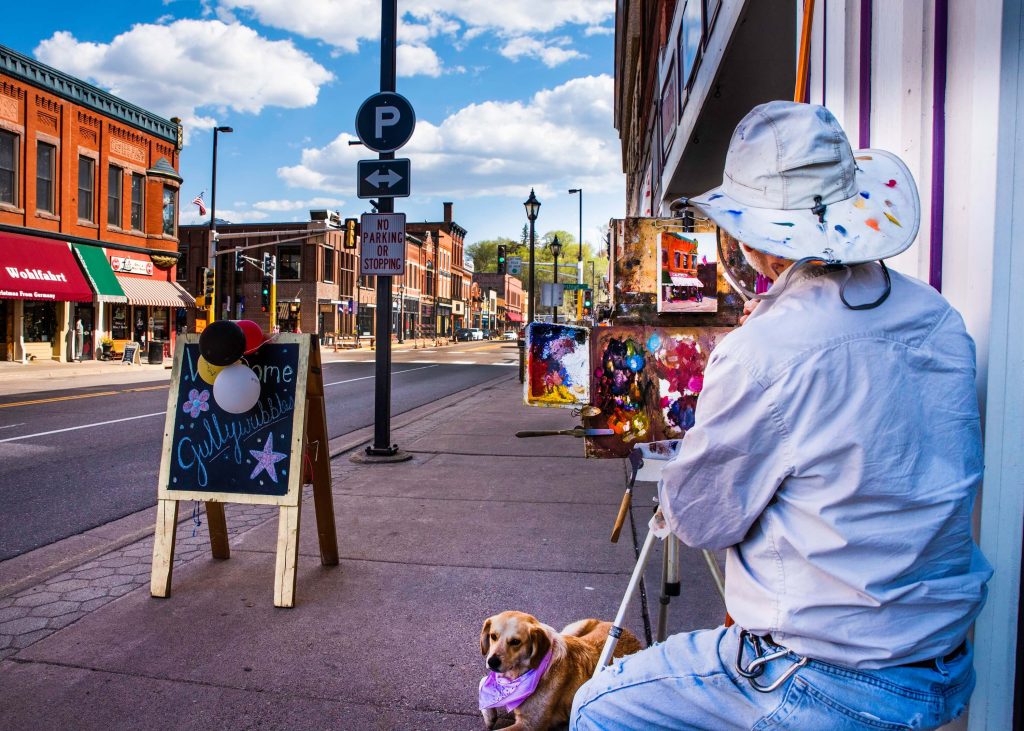 Man with dog painting the main street in downtown Stillwater. 