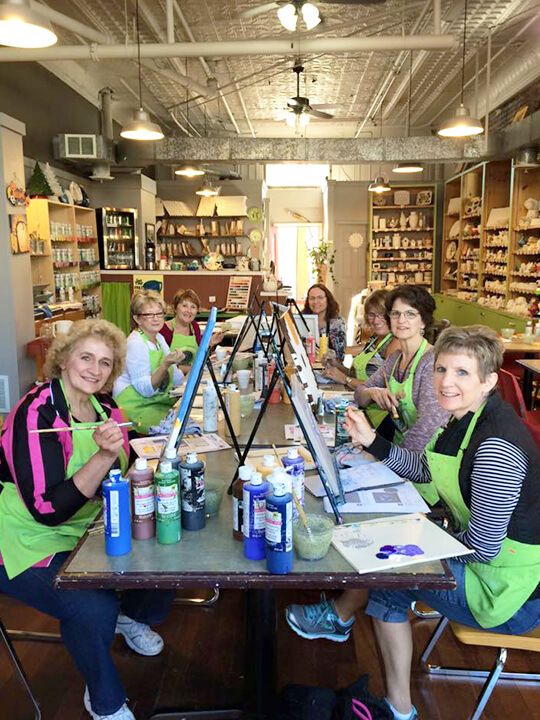 Seven women working on a DIY painting project at Kari's Paint and Create. 